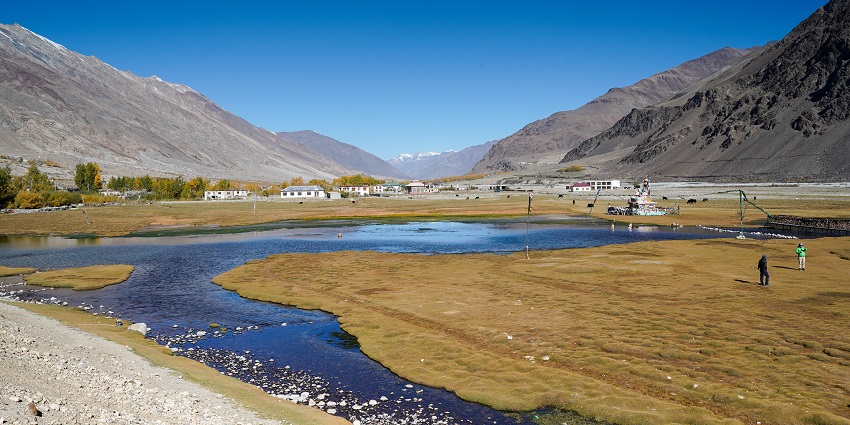 Picturesque view of a lake surrounded by mountains and houses under clear blue sky
