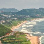 An aerial picture of a coastline with green hills and residential apartments all around