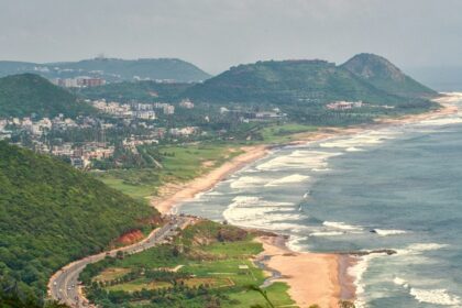 An aerial picture of a coastline with green hills and residential apartments all around