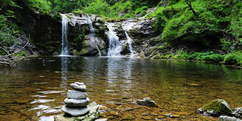 A fantastic view of the cascading Kapil Dhara Waterfall surrounded by lush greenery.