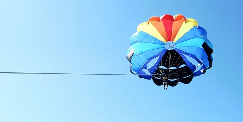 An amazing view of a colourful parachute in the clear blue sky during the daytime.