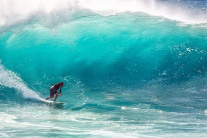 A person surfing amidst the shores, indulging in an adventure of a lifetime.