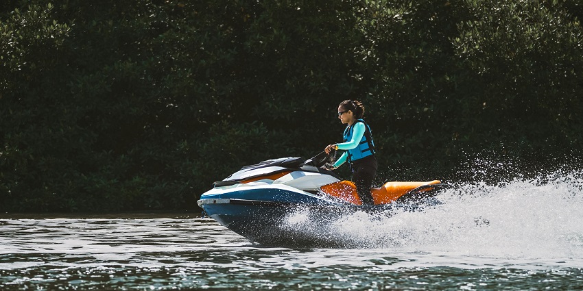 A breathtaking view of a woman enjoying jet skiing over a sparkling water body in the day.
