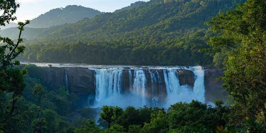Image of majestic Athirapally Waterfalls cascading through lush greenery in Kerala, India.