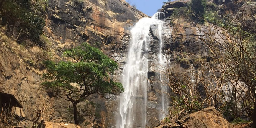 A scenic view of Akasa Gang Fall, showcasing cascading water amidst lush greenery.