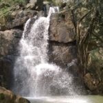 A grand view of waterfalls in Orissa with cascading water between the greens.