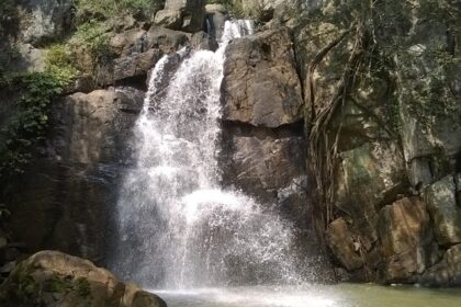 A grand view of waterfalls in Orissa with cascading water between the greens.