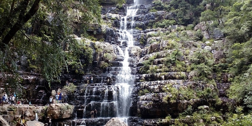 Image of a stunning waterfall cascading down rocky cliffs surrounded by lush greenery.