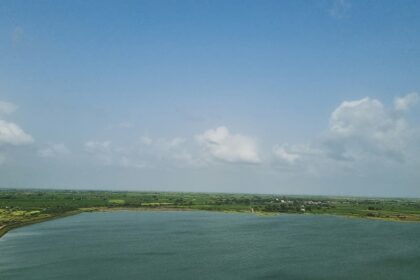 Picturesques view of a lake surrounded by lush greenery under clear blue sky in Jamnagar