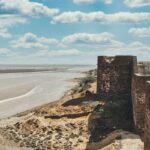 A breathtaking view of a historical fort with an azure water body on the side of it.