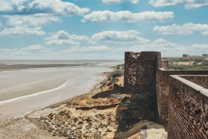 A breathtaking view of a historical fort with an azure water body on the side of it.