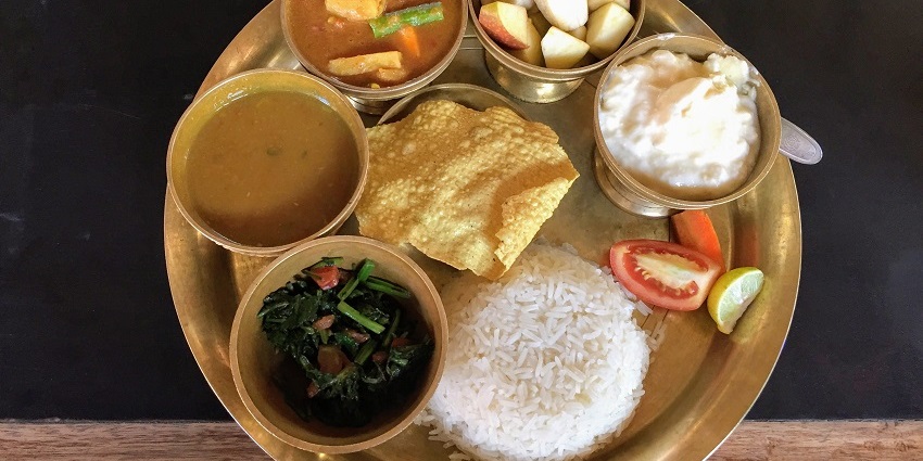 A plate of Nepali dal-bhat-tarkari, featuring rice, lentil soup, and mixed vegetables.