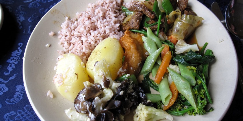 Traditional Bhutanese cuisine featuring red rice, vegetables, and chilli dishes.