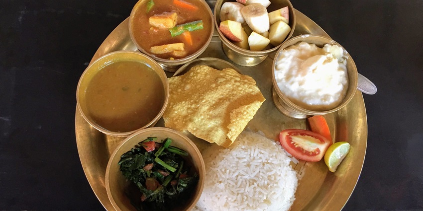 A traditional Nepali meal of dal, bhat, and tarkari served on a vibrant plate.