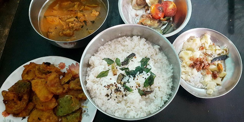 A table set with four bowls of food, representing the culinary offerings in Berhampur.