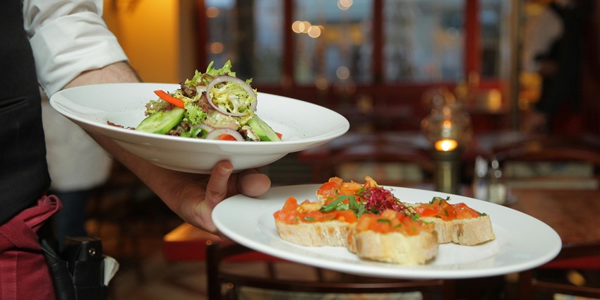 Snapshot of a person holding pastry dishes on a white ceramic plate in a restaurant