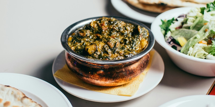A mouthwatering view of a brass utensil served with cooked vegetables and flatbreads.