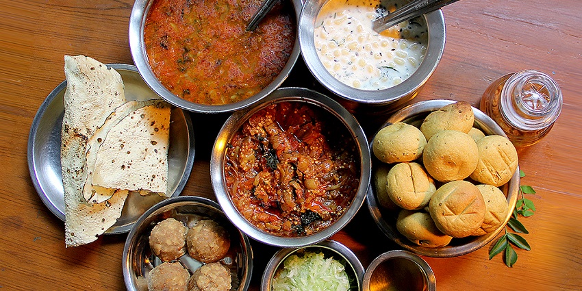 A traditional plate of Daal Bati showcasing local cuisine for visitors served nearby