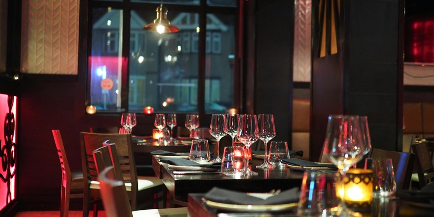 A picture of a restaurant from inside with a table setting and crockery placed on top