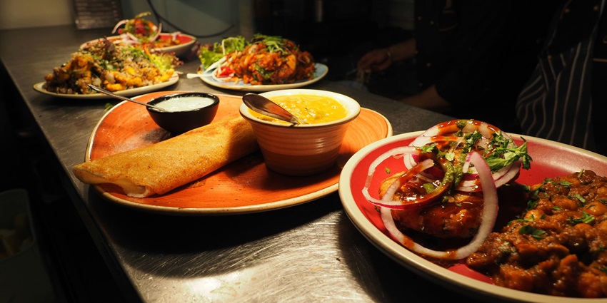 A mouth-watering view of a table served with different cooked dishes and flatbreads.