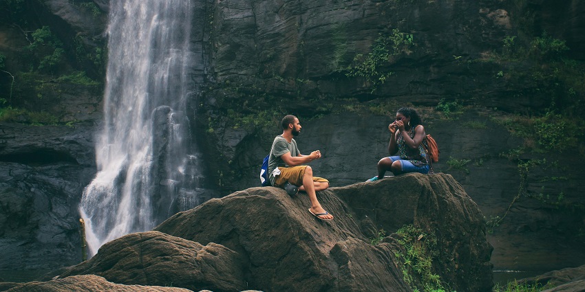 Two people near the waterfall during their trekking, taking rest and having some food