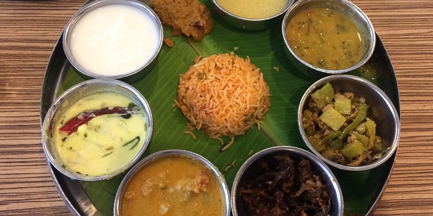 Image of Andhra meal in a restaurant served on a plate and banana leaf