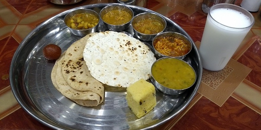 Image of dinner consists of Rice, dal, sambar, 3 types of vegetable curries, Gulab jamun & chhas