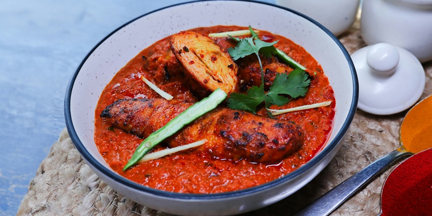 A mouth-watering view of a white ceramic bowl served with a cooked dish on a table.