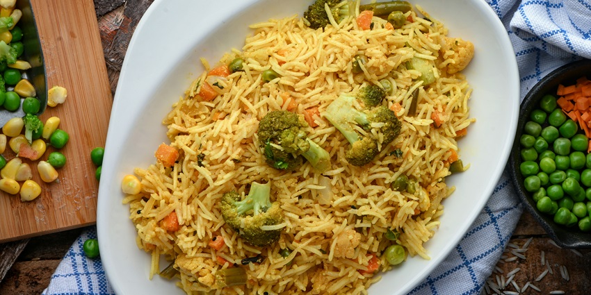 A mouth-watering view of a bowl of rice garnished with broccoli, peas and carrots.