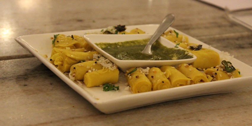 A plate of savoury Khandvi with chutney, a popular Gujarati dish, one of the tasty items you can enjoy