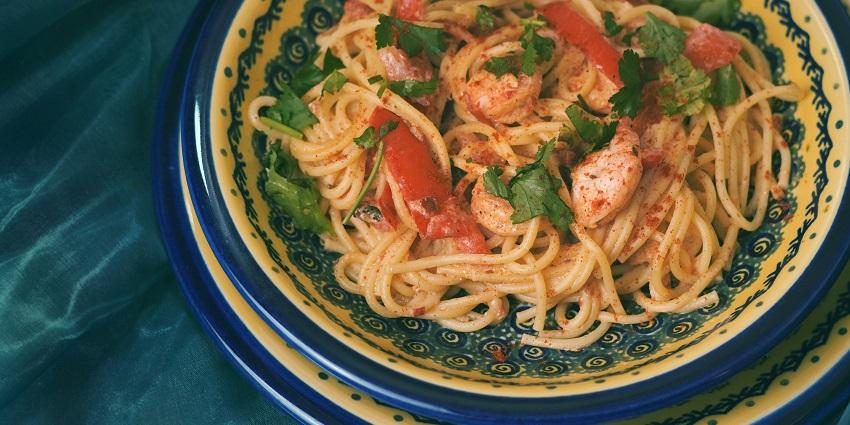 Image of prawns with noodles served on a plate with coriander toppings