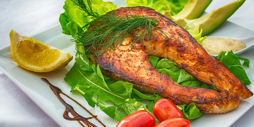 A plate of cooked meat accompanied by a colourful assortment of fresh vegetables
