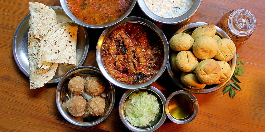 Savour delicious Madhya Pradesh cuisine like traditional dishes served on a large platter, including curries, rice, roti, and accompaniments.