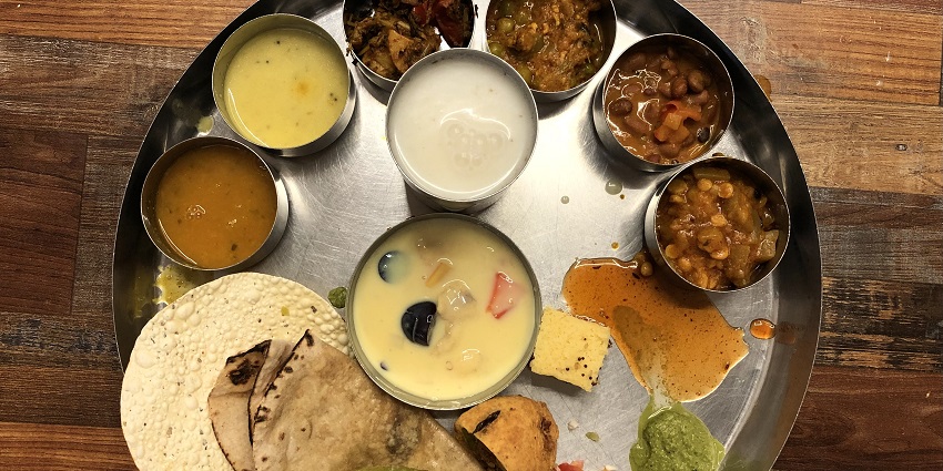 A traditional Rajasthani Thali with many regional delicacies presented at a restaurant.