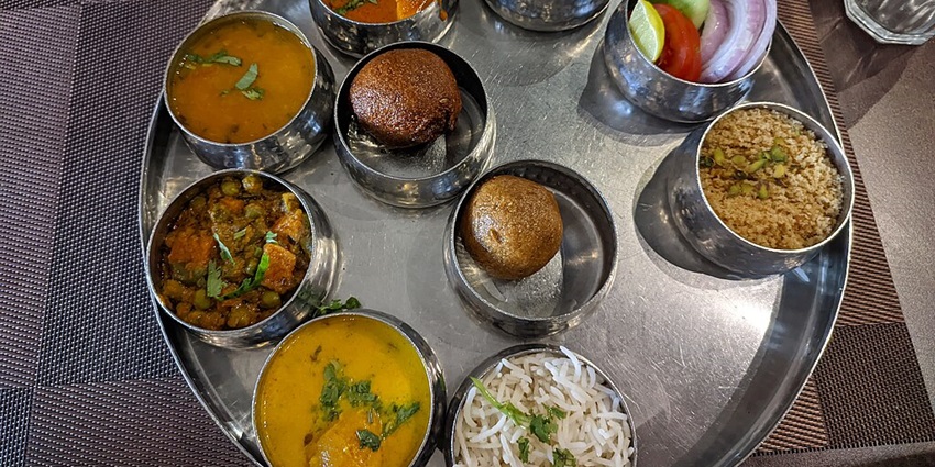 Traditional Rajasthani thali featuring an assortment of dishes including dal, sabzi, roti, rice etc.