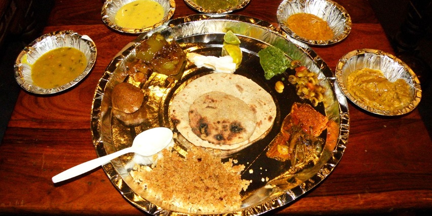 A traditional Rajasthani thali with a variety of dishes served on a round metal plate.