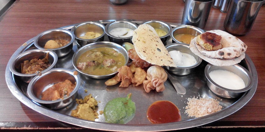 A Rajasthani style of meal is served on a large circular platter in traditional Rajasthani way