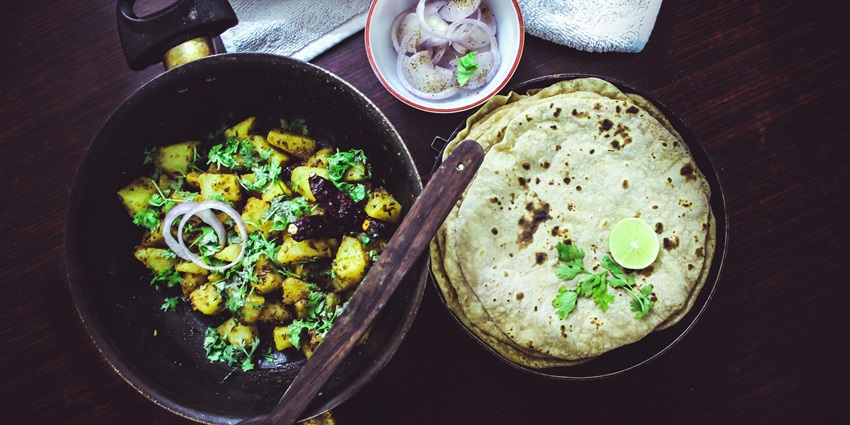 A mouth-watering view of a plate served with a cooked dish with flatbreads on the side.