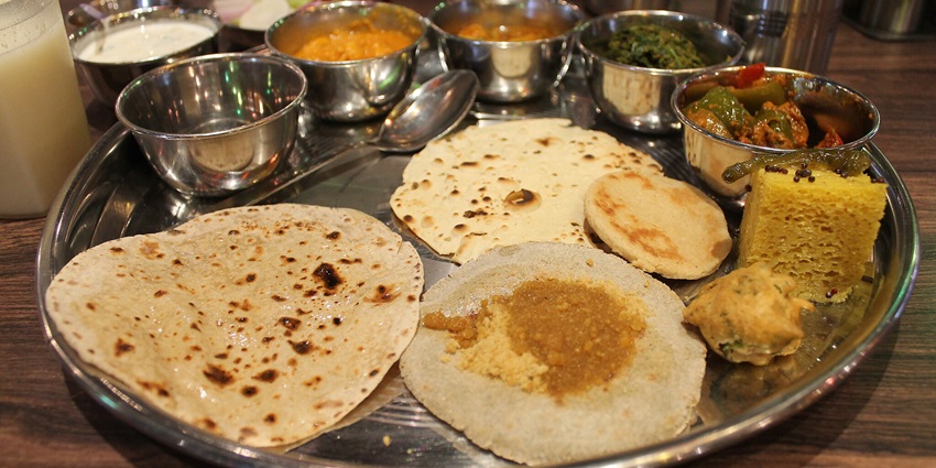 A traditional Rajasthani thali featuring a variety of dishes, like dal, curries, rice etc.