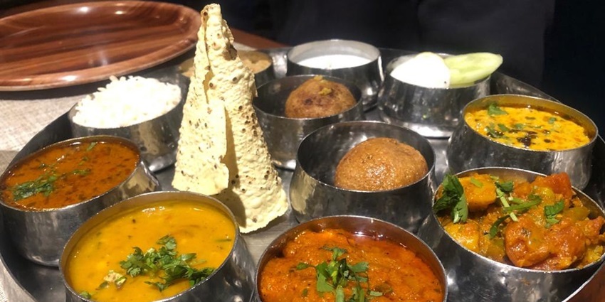 A colorful assortment of traditional Rajasthani dishes, including curries, breads, and chutneys.