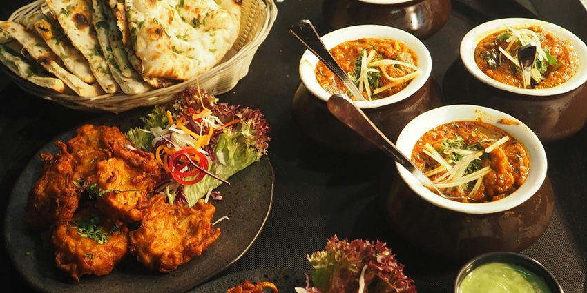 A mouthwatering view of a table served with delicious Indian food and flatbreads.