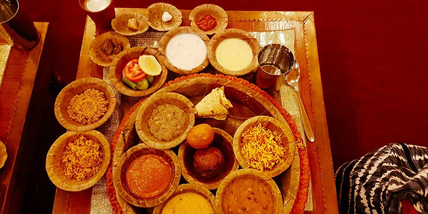A Rajasthani thali featuring a variety of dishes like dal, sabzi, roti, rice, and sweets
