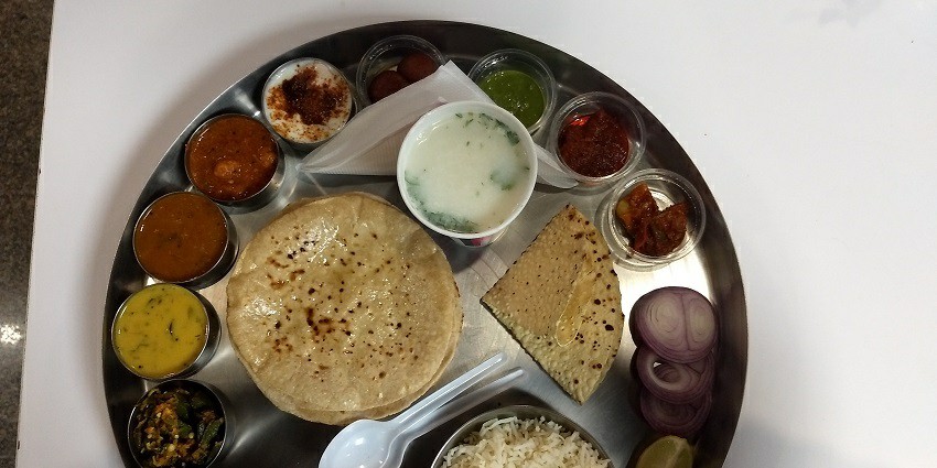 A traditional Rajasthani thali with dal, sabzi, roti, rice, and sweets.