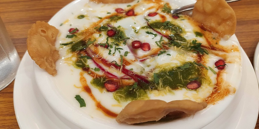 The image is of Papdi Chaat made from curd, papdi, tamarind chutney, green chutney