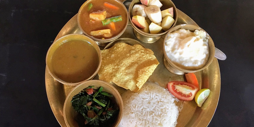 A traditional Nepali meal of dal bhat tarkari is presented on a metal plate