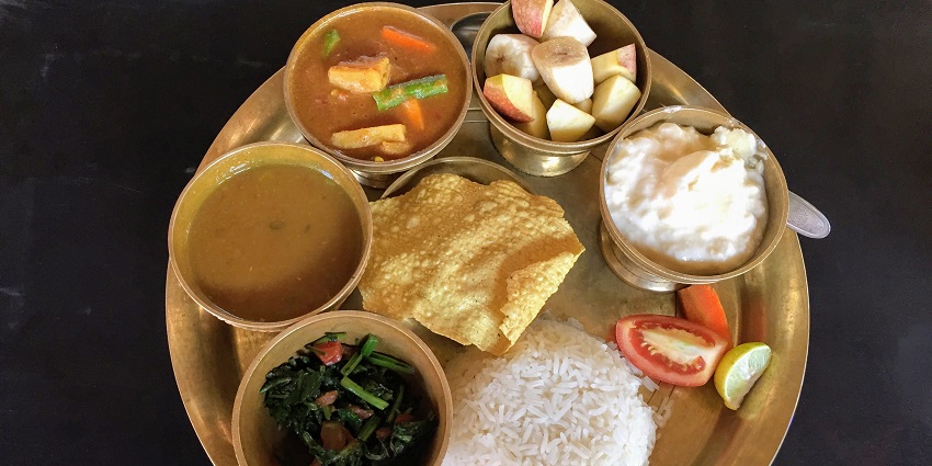 A Nepali meal comprising steamed rice (bhat), lentil soup (dal), and a variety of vegetable curries (tarkari)
