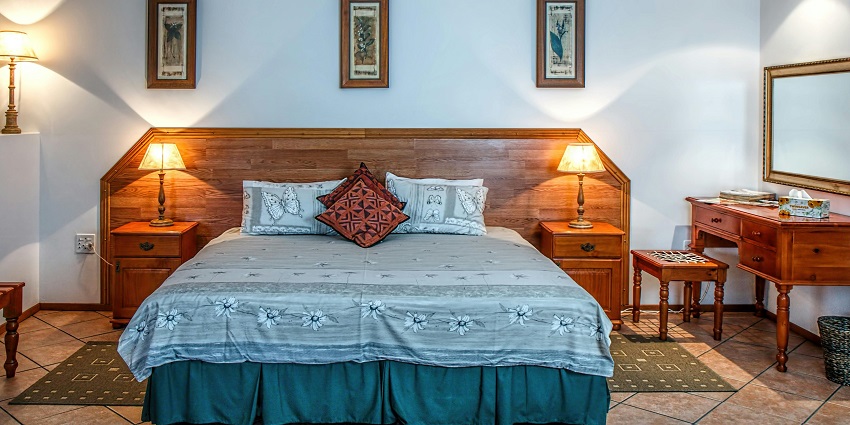 A stunning view of a bedroom with a bed lined with blue sheets and lamps on the side.