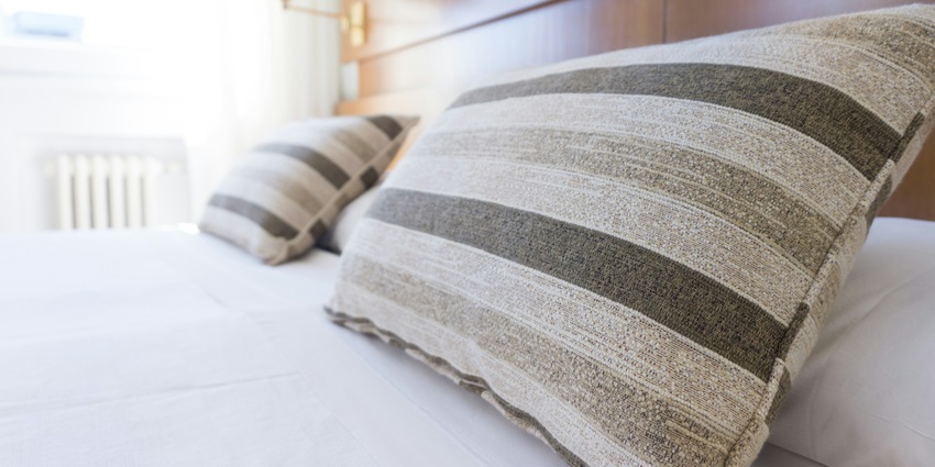 A stunning interior view of a bed with white sheets and colourful pillows on top of it.