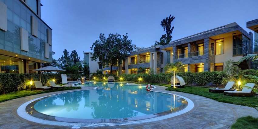 View of a pool in a hotel in Gujarat, with luxurious rooms all around it