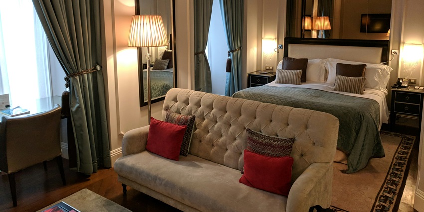 A stunning interior view of a bedroom with a white couch in front of a brown bed.